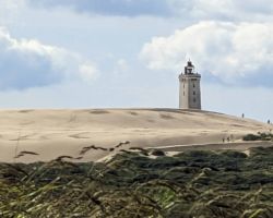 Ein Leuchtturm steht auf einer Sanddüne.