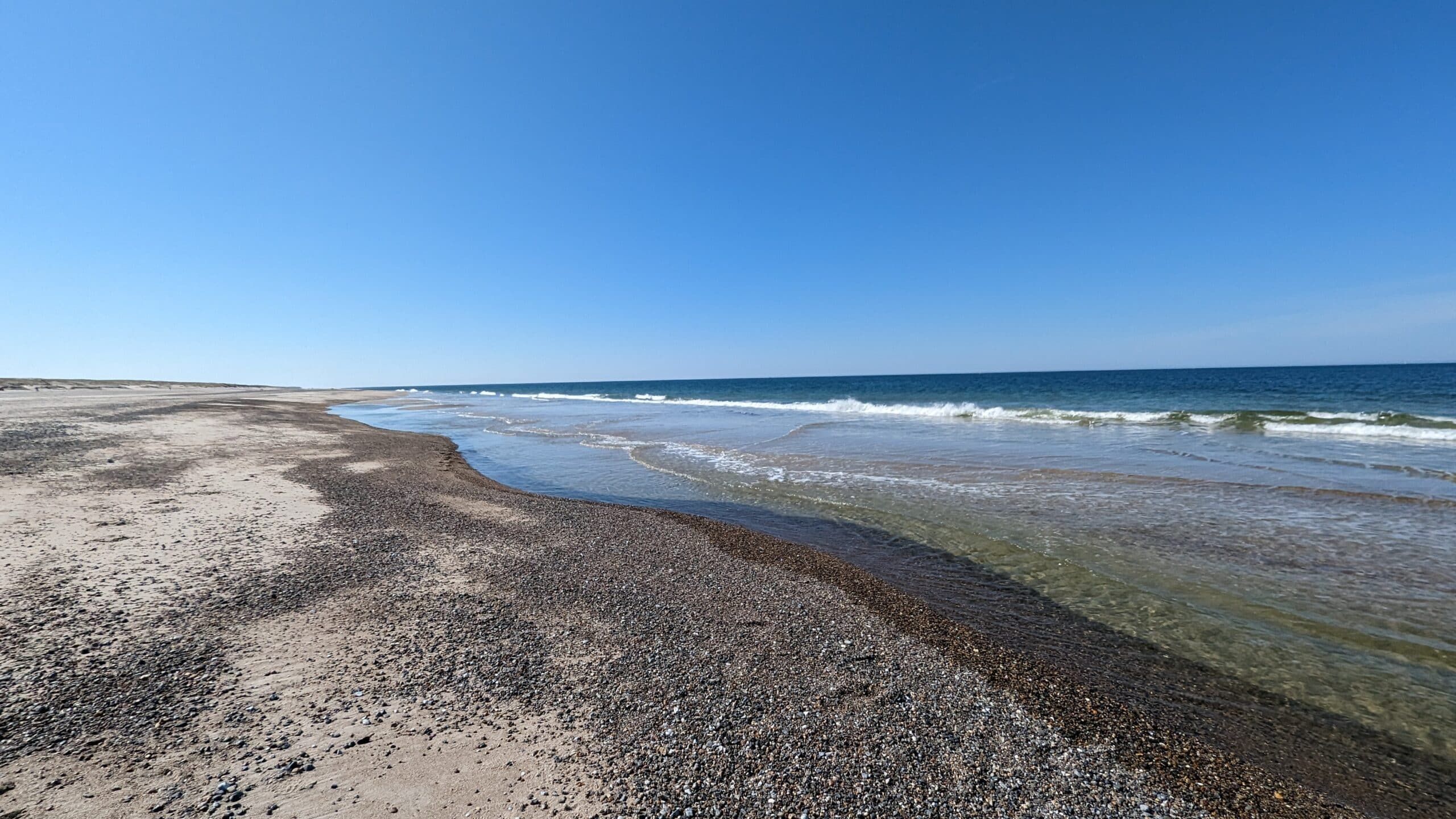 Ein Strand mit Sand und Wasser an einem sonnigen Tag.