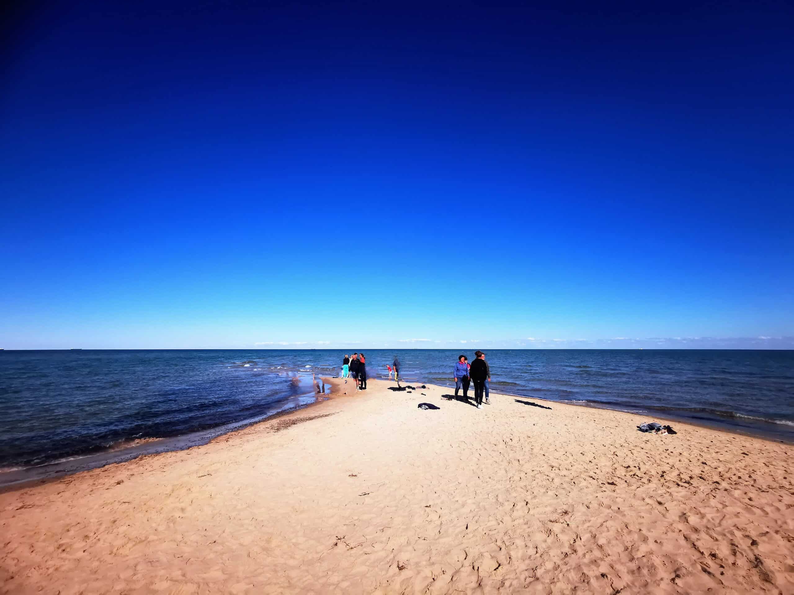 Eine Gruppe von Menschen steht an einem Sandstrand.