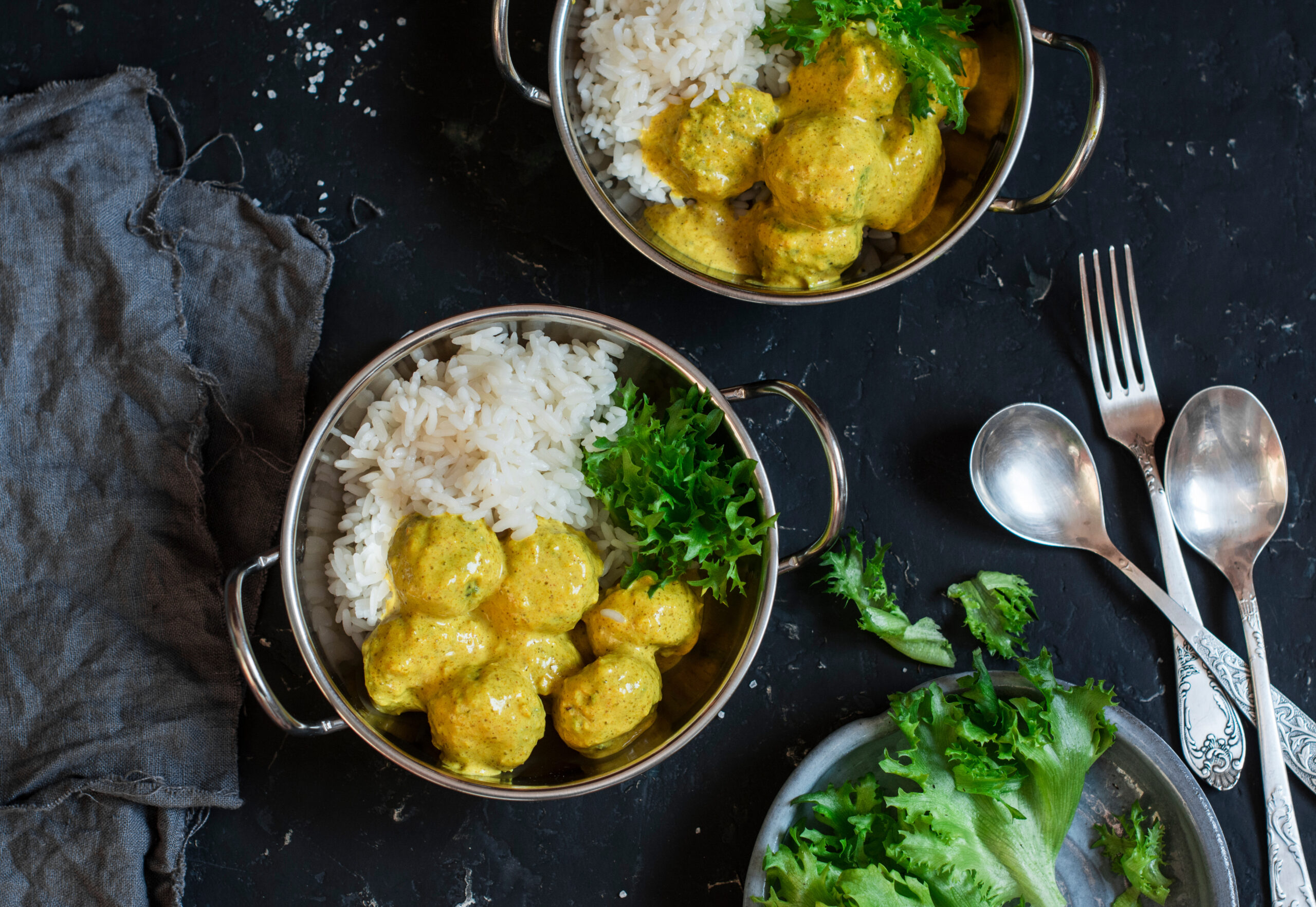 Zwei Schüsseln Hühnercurry mit Reis auf einem Tisch.
