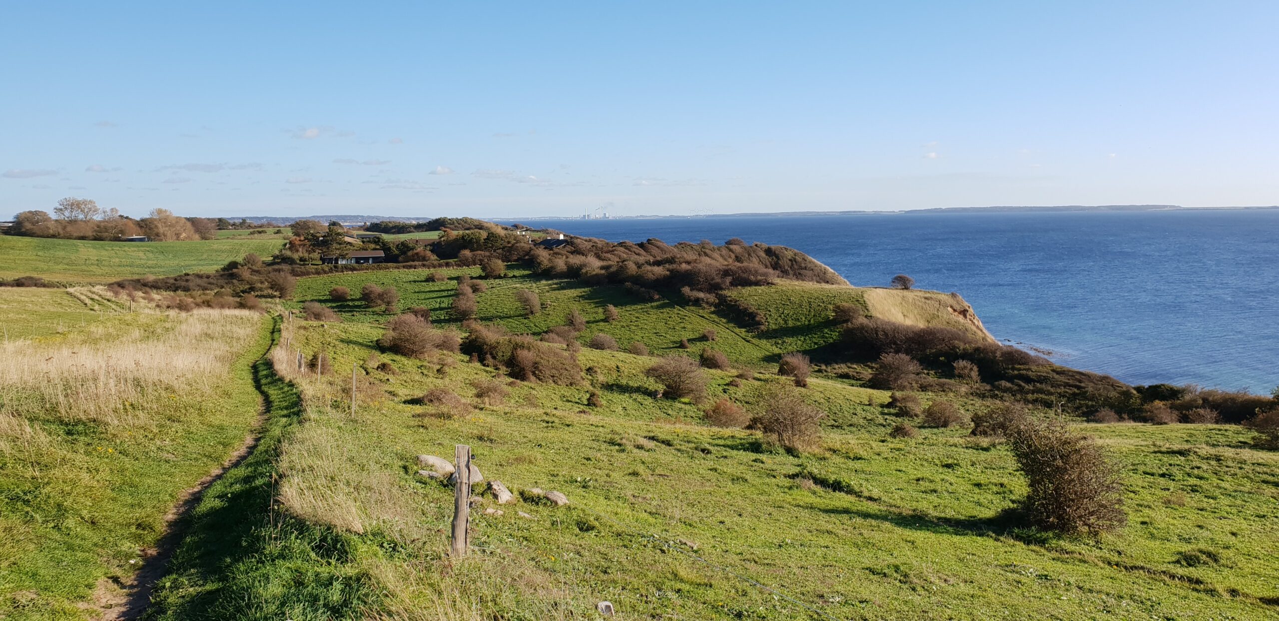 Eine Luftaufnahme eines grasbewachsenen Hügels mit dem Meer im Hintergrund.