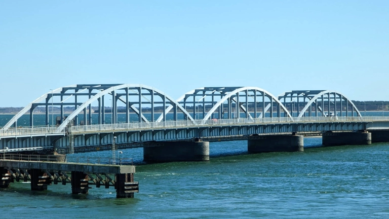 Eine Brücke über das Wasser mit einer Brücke darüber.