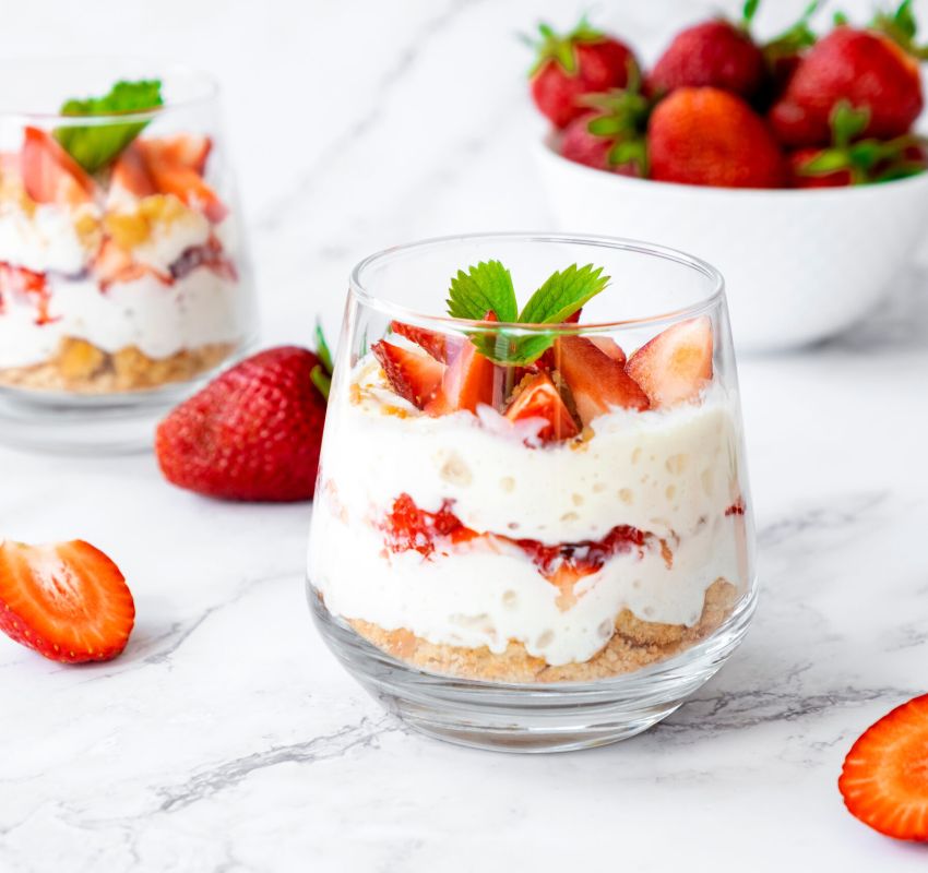Zwei Glasdesserts mit Erdbeeren und Schlagsahne.